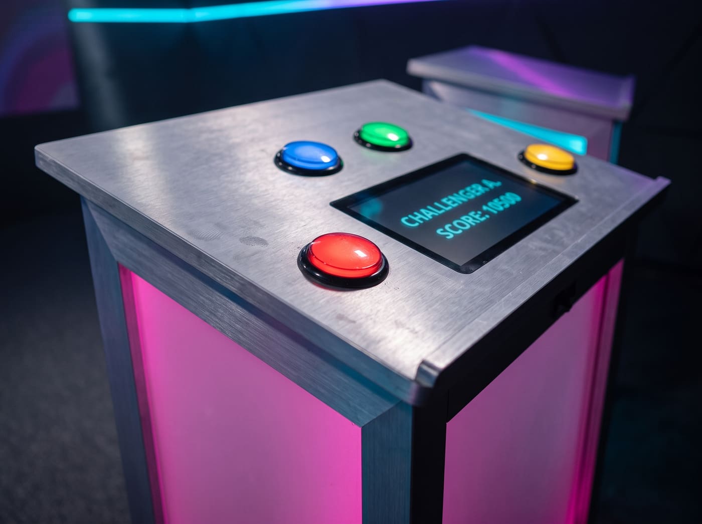 Un pupitre en aluminium brossé avec ses quatre boutons arcade lumineux et son écran tactile